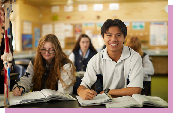 Student smiling at desk in classroom