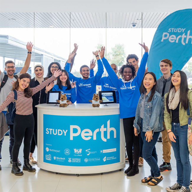 Group of smiling people around desk at airport