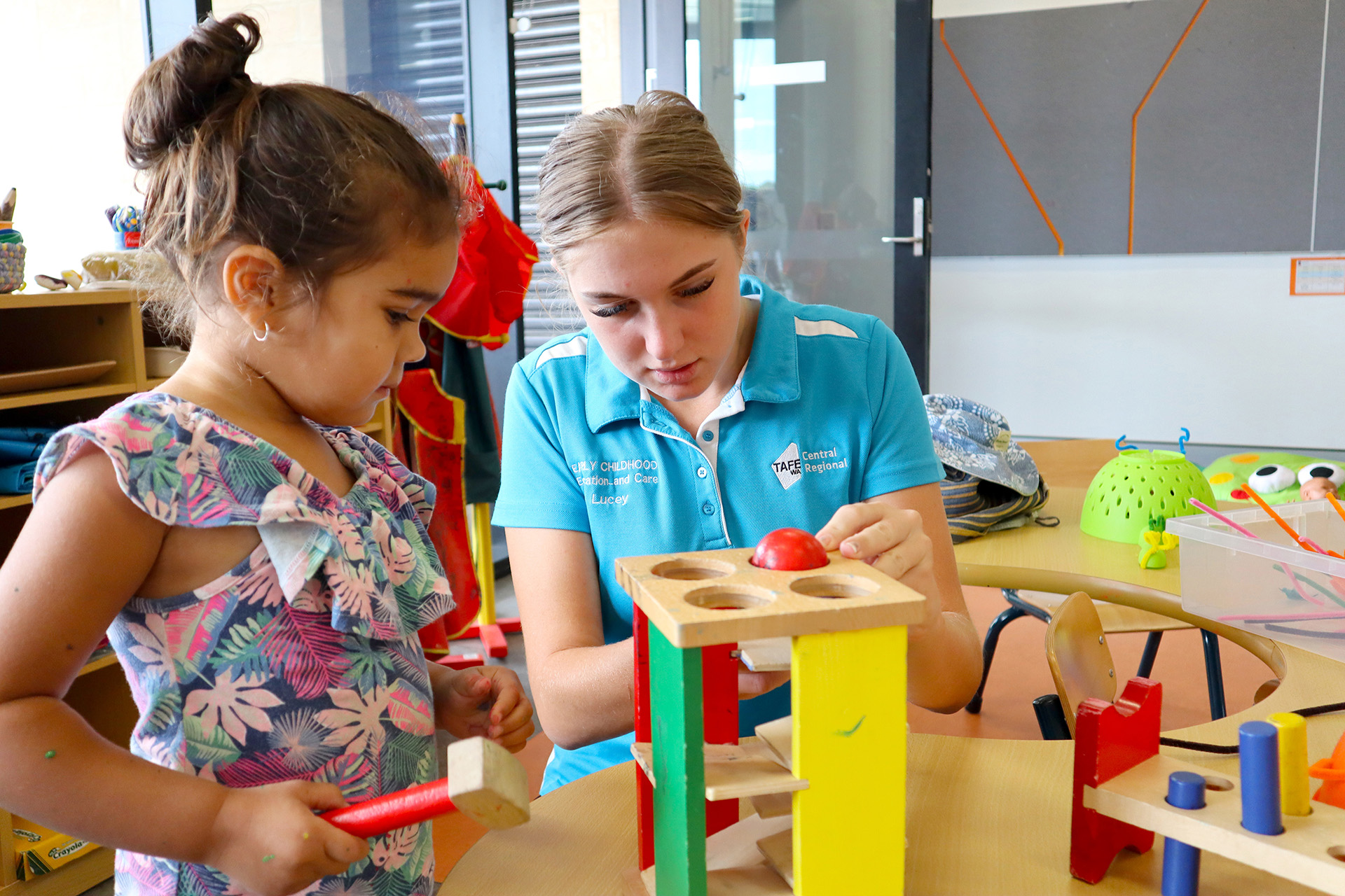 TAFE student assisting child with play equipment