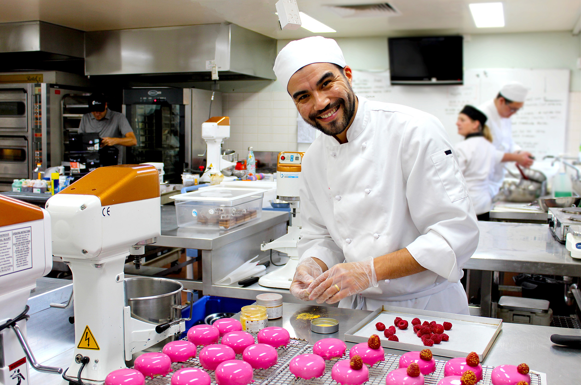 students in kitchen attire handling dessert