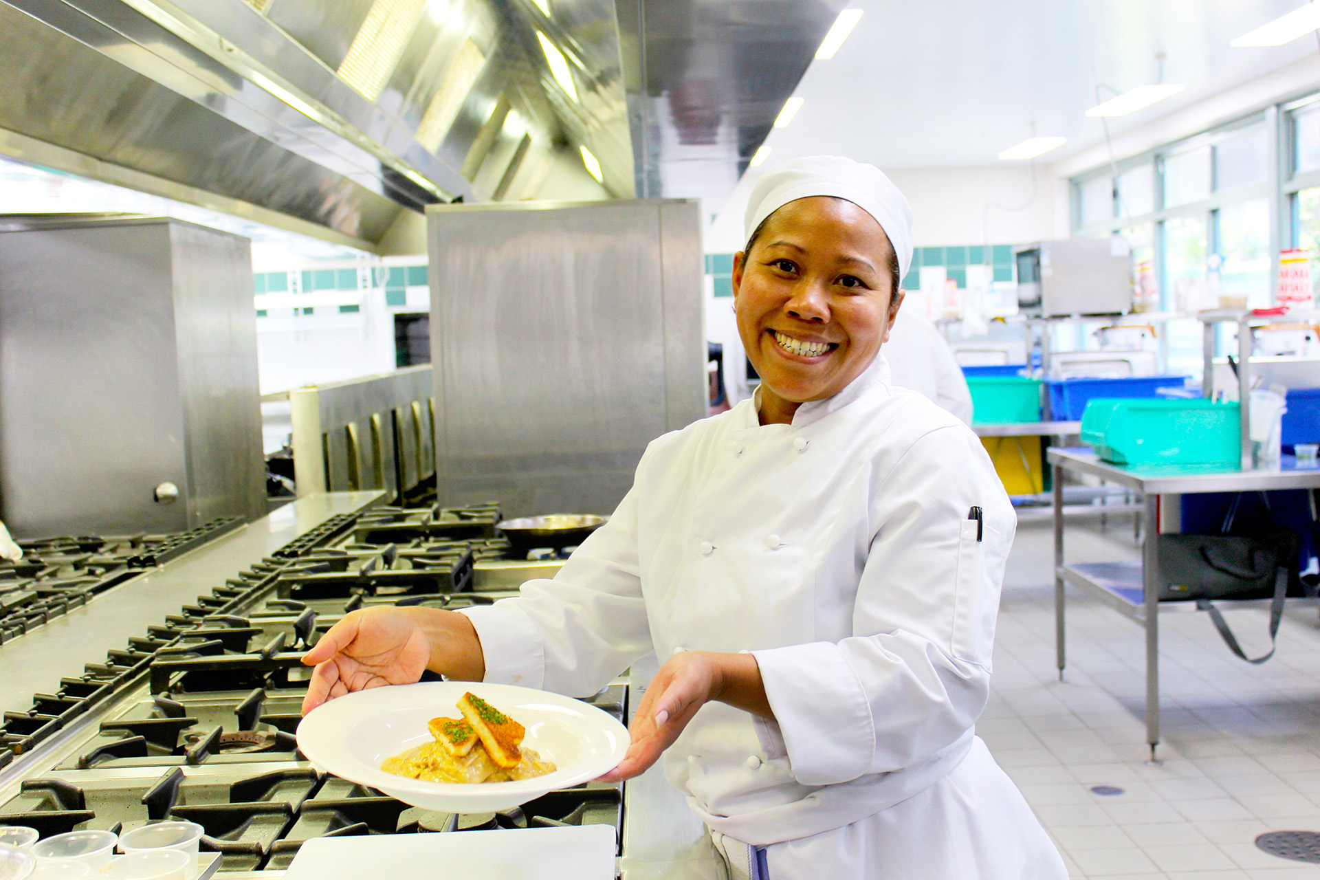 student holding plate of food in kitchen
