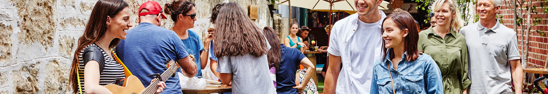 People at markets watching a woman playing acoustic guitar