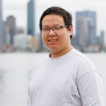 Student Buyan Erdene Od looks towards the camera smiling. In the background is the Perth city skyline.