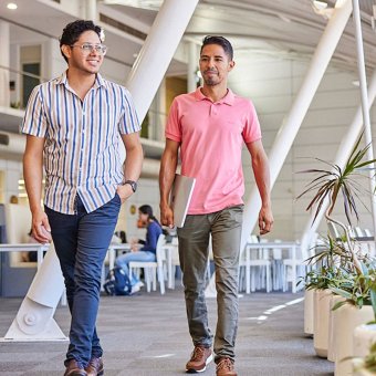 Two male students are walking towards the camera smiling. They are walking at East Perth campus.