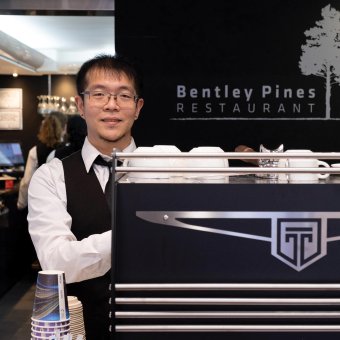 Student Jackson stands behind a coffee machine at Bentley Pines Restaurant
