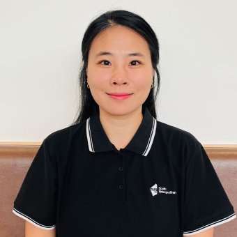 Lecturer Jinjoo Park from Remedial Massage sits on a chair, facing the camera. The photo is from arms up. She wears a black South Metropolitan shirt. She smiles towards the camera.