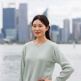Student Lhaki stands at South Perth foreshore. She's looking towards the camera smiling.