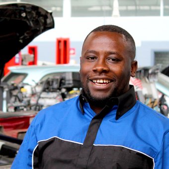 TAFE international student Lorenzo Werk, standing in front of cars at TAFE automotive training facilities