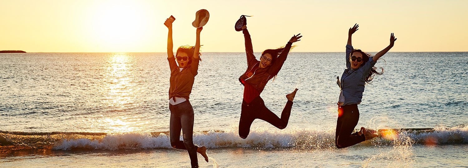 People jumping in air at beach in Geraldton with sunset in background