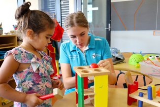 TAFE student assisting child with play equipment