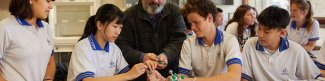 Group of schools students in classroom holding science materials