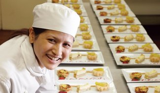 Person in cooking attire in front of prepared food