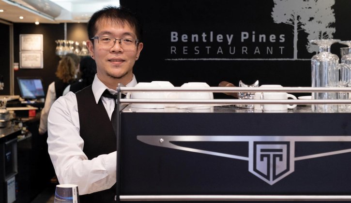 Student Jackson stands behind a coffee machine at Bentley Pines Restaurant