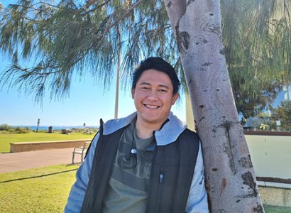 TIWA student Jong poses next to a tree