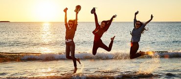 People jumping in air at beach in Geraldton with sunset in background